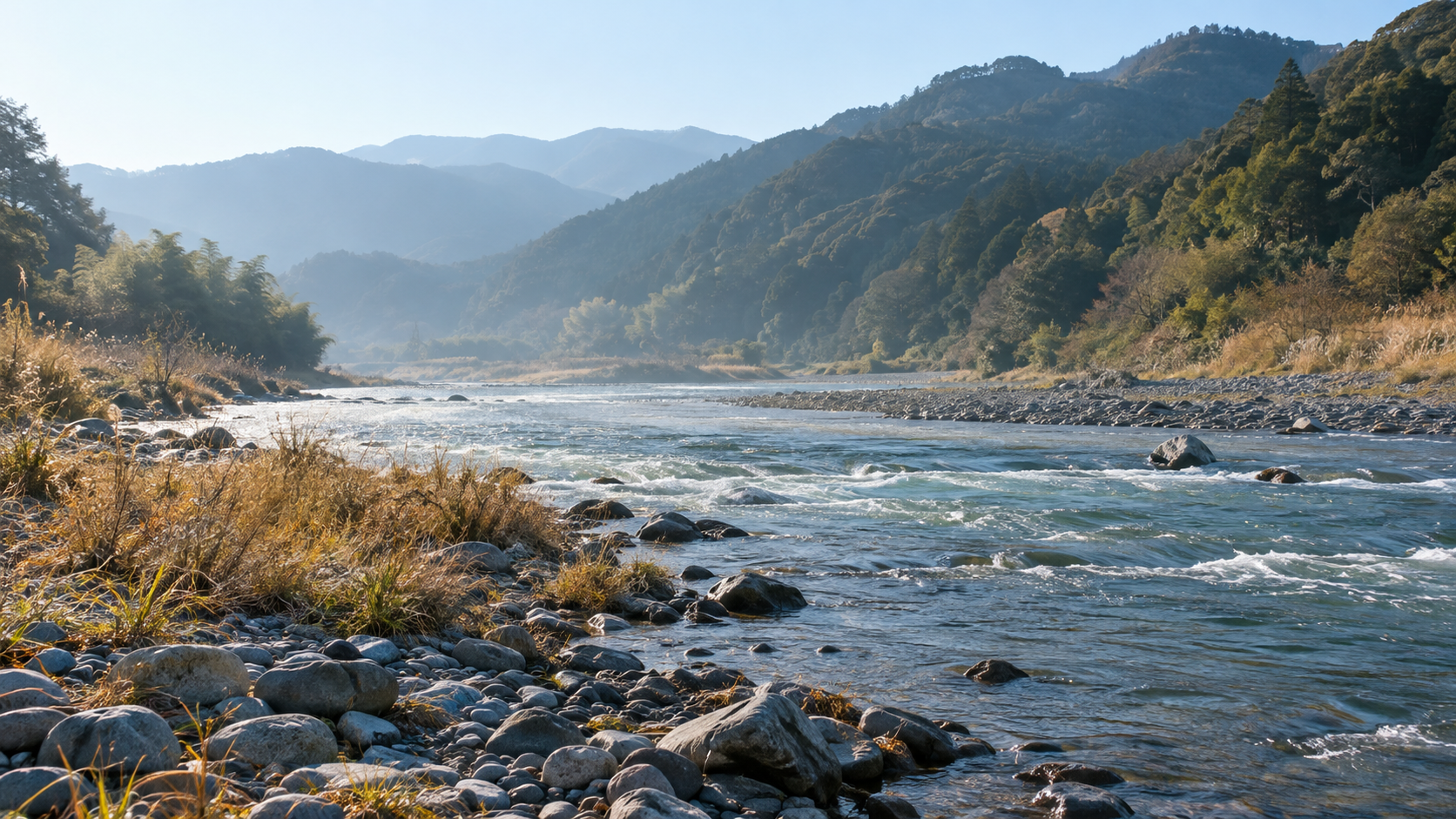 岩と葦のある静かな川岸と遠くの山並み