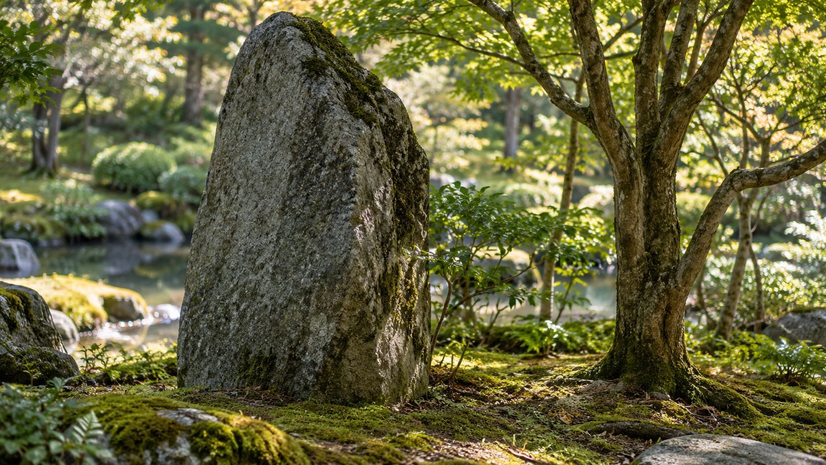 木々の間に、文字のない大きな自然石が立つ創作景観