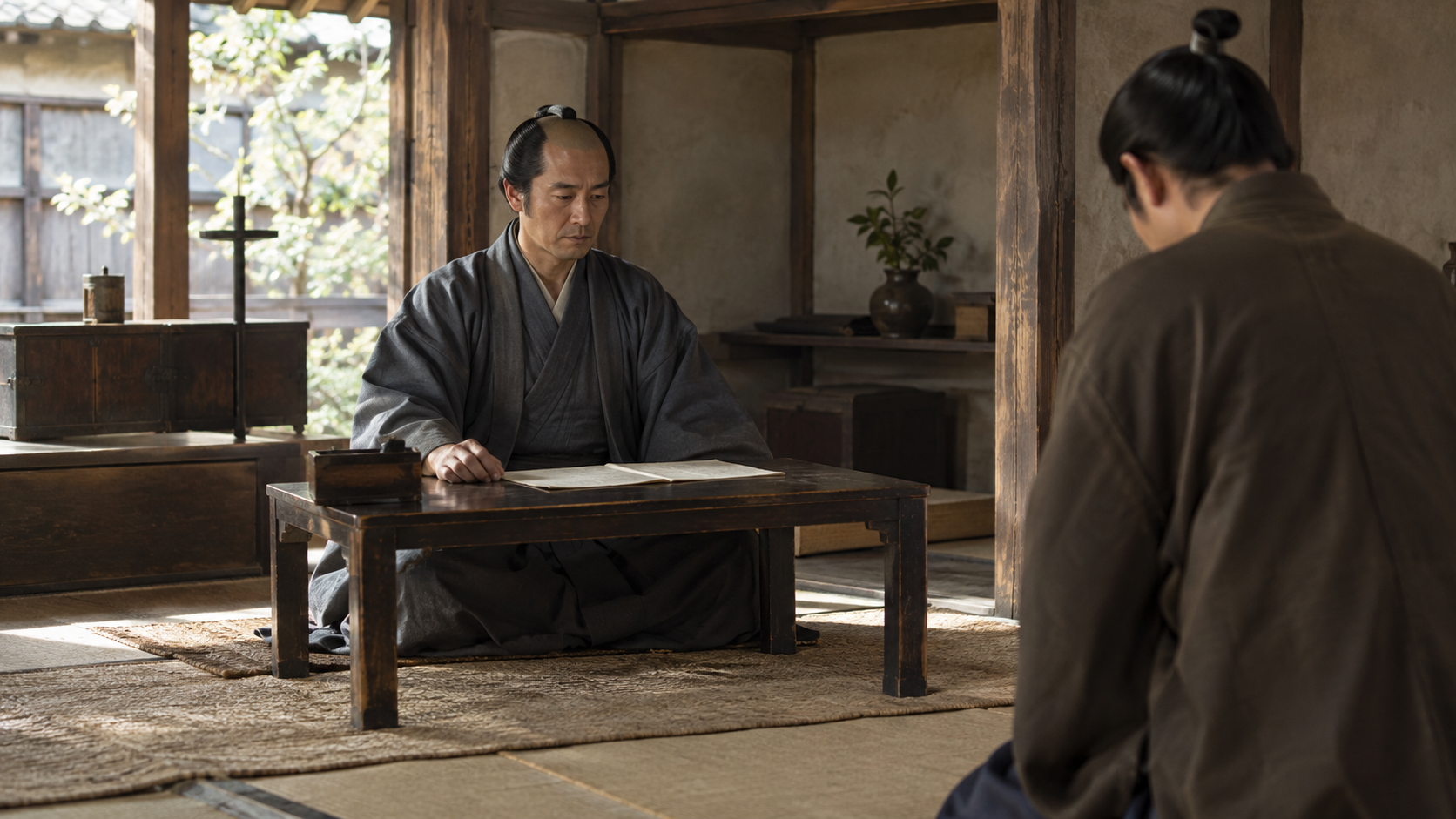 木の机と紙を前に座る匿名人物と向かい合う人の創作情景