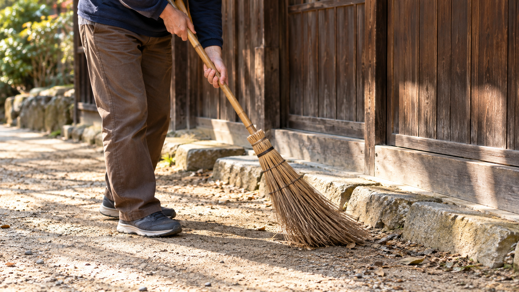 木造家屋の前を掃く現代の架空人物